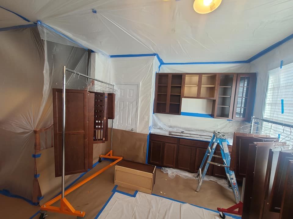 Kitchen under renovation, with plastic sheeting, open cabinets, and a blue ladder on the floor.