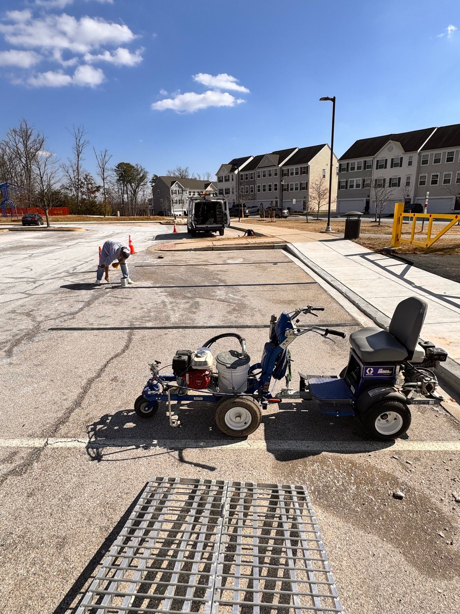 Road construction site with workers, utility cart, and unfinished pavement under a blue sky