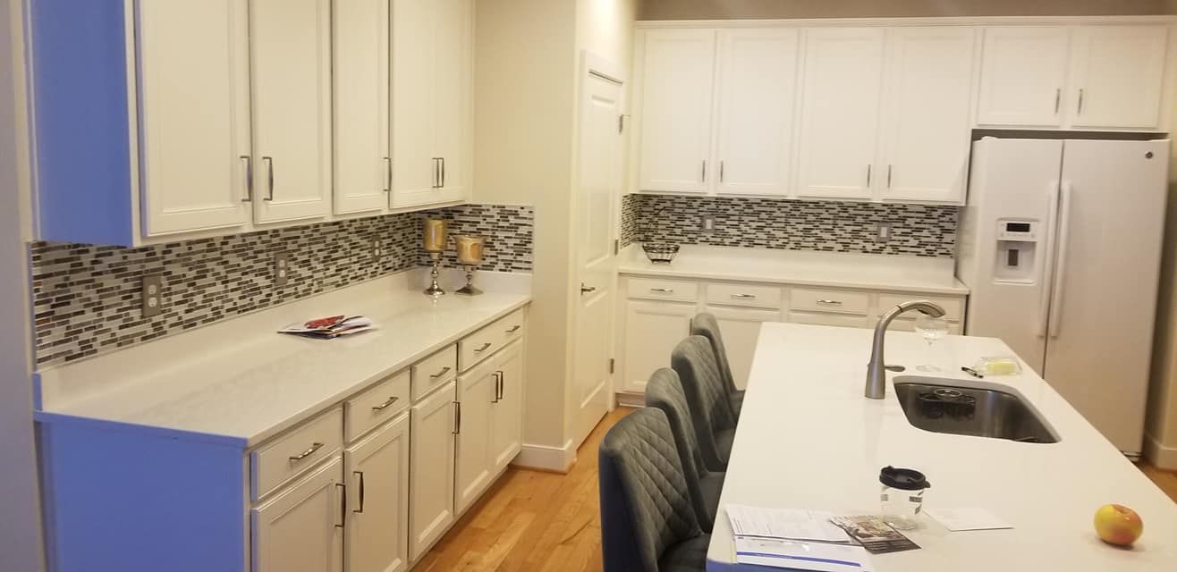 Bright kitchen with white cabinets, mosaic backsplash, long counter, and dining table with chairs