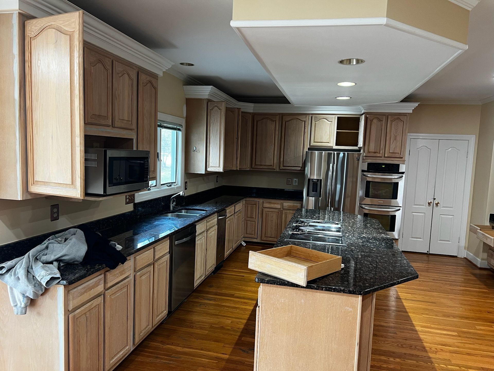 Modern kitchen with wood cabinets, black countertops, stainless appliances, and a central island.