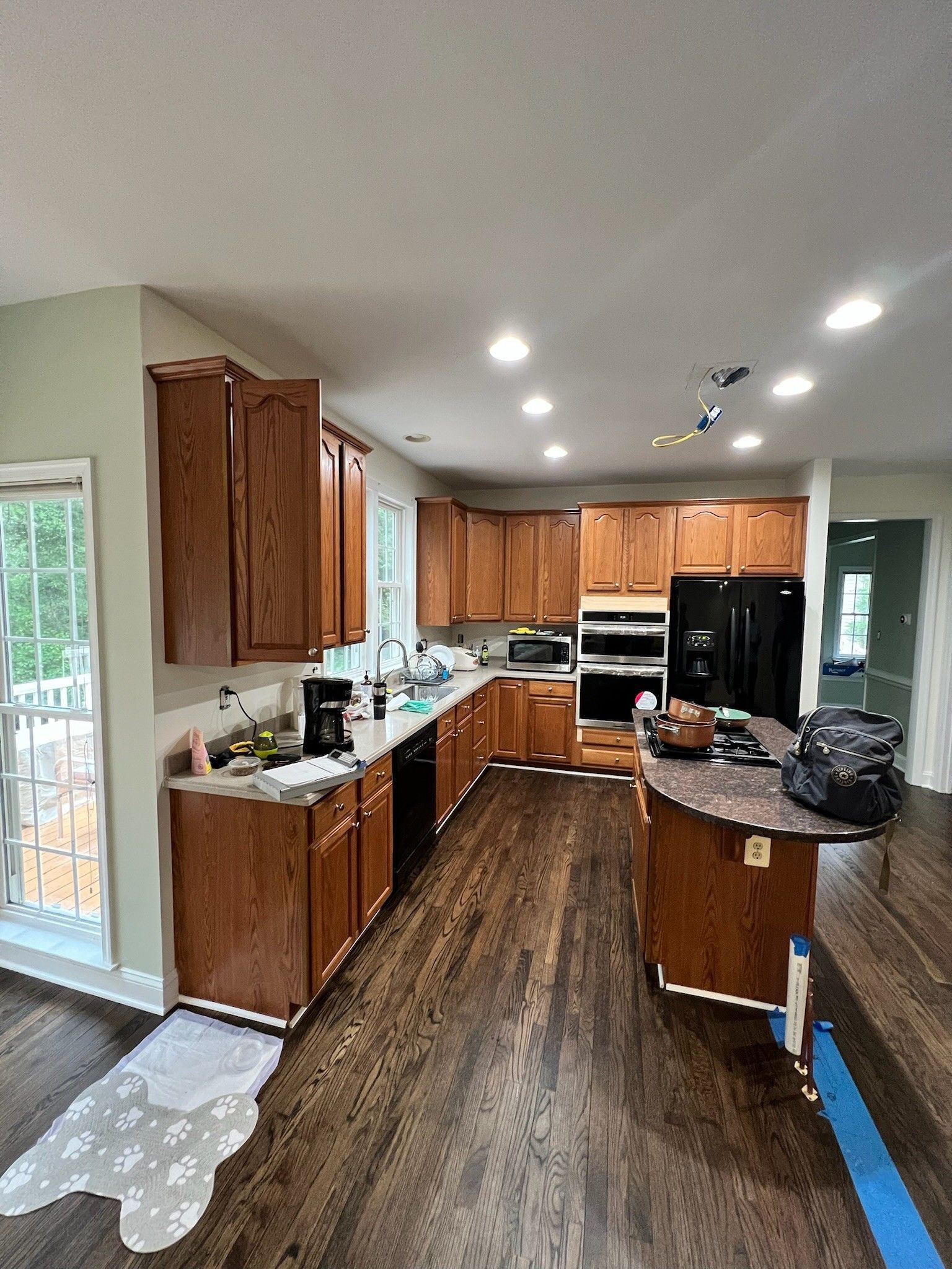 Bright kitchen with wooden cabinets, dark floors, and an island under recessed ceiling lights.