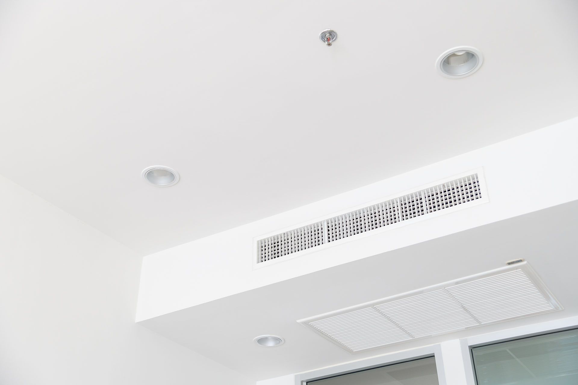 A white air conditioner is mounted to the ceiling of a room.