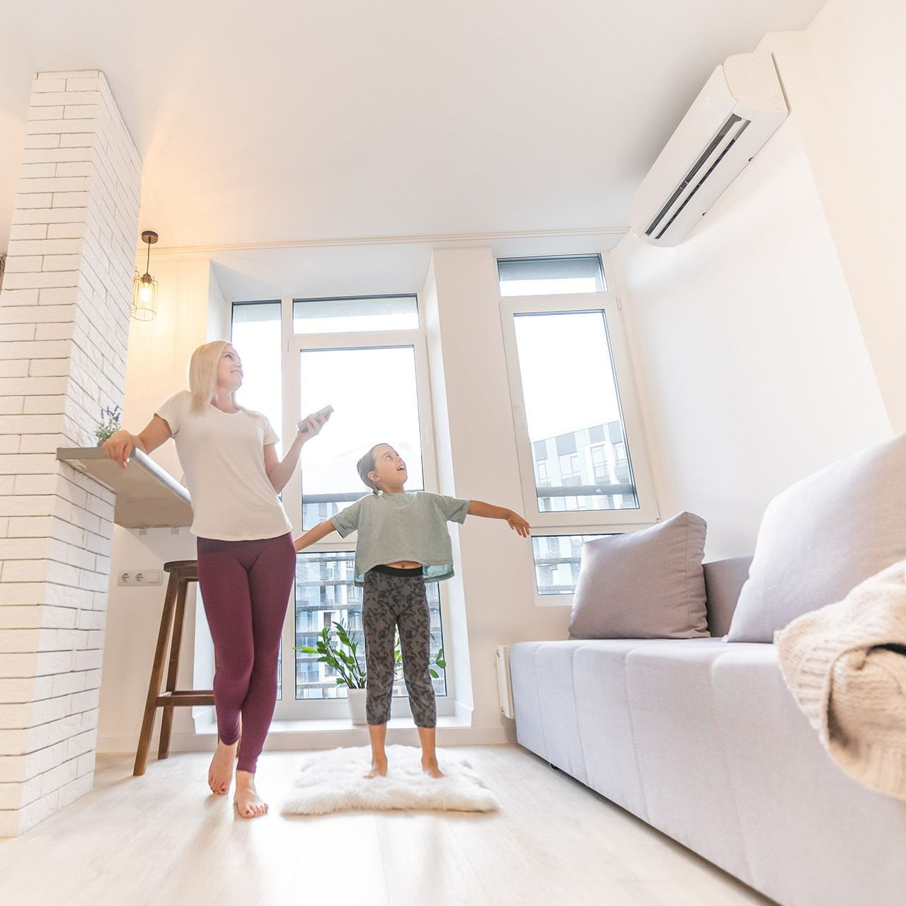A woman and child are standing in a living room next to a couch.