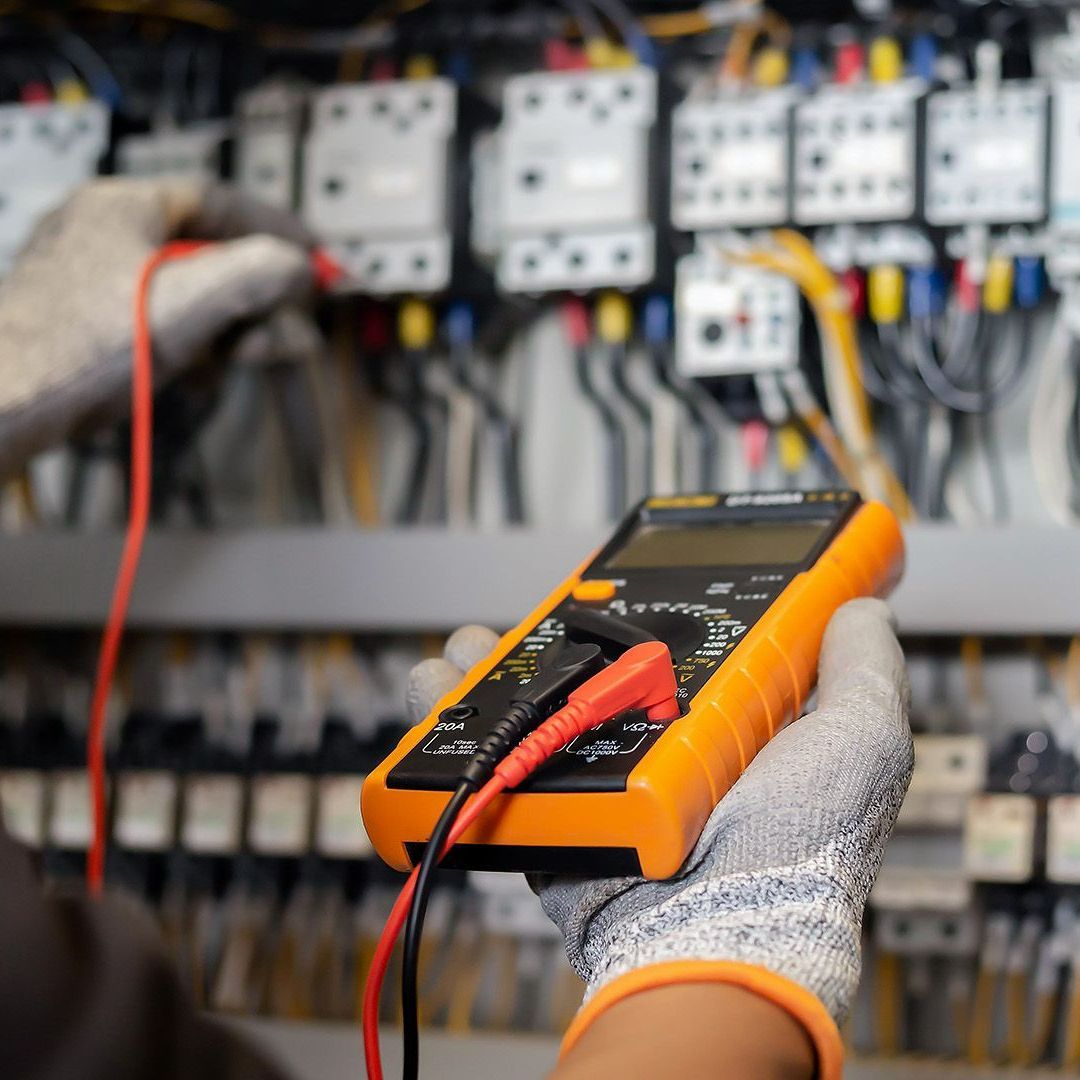 A person is holding a digital multimeter in their hand.
