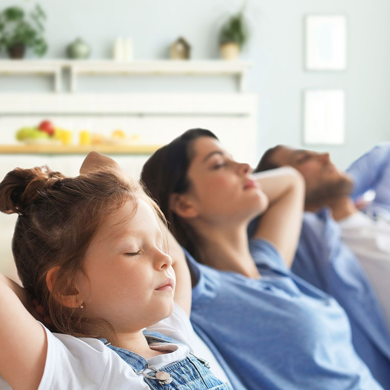 A family is laying on a couch with their arms behind their head.