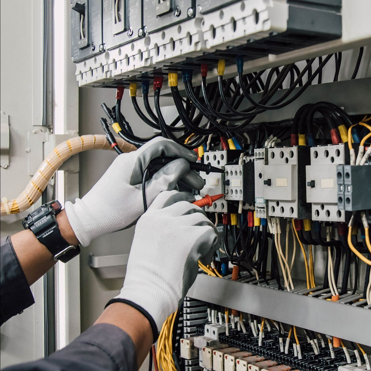 A person is working on an electrical panel with gloves on
