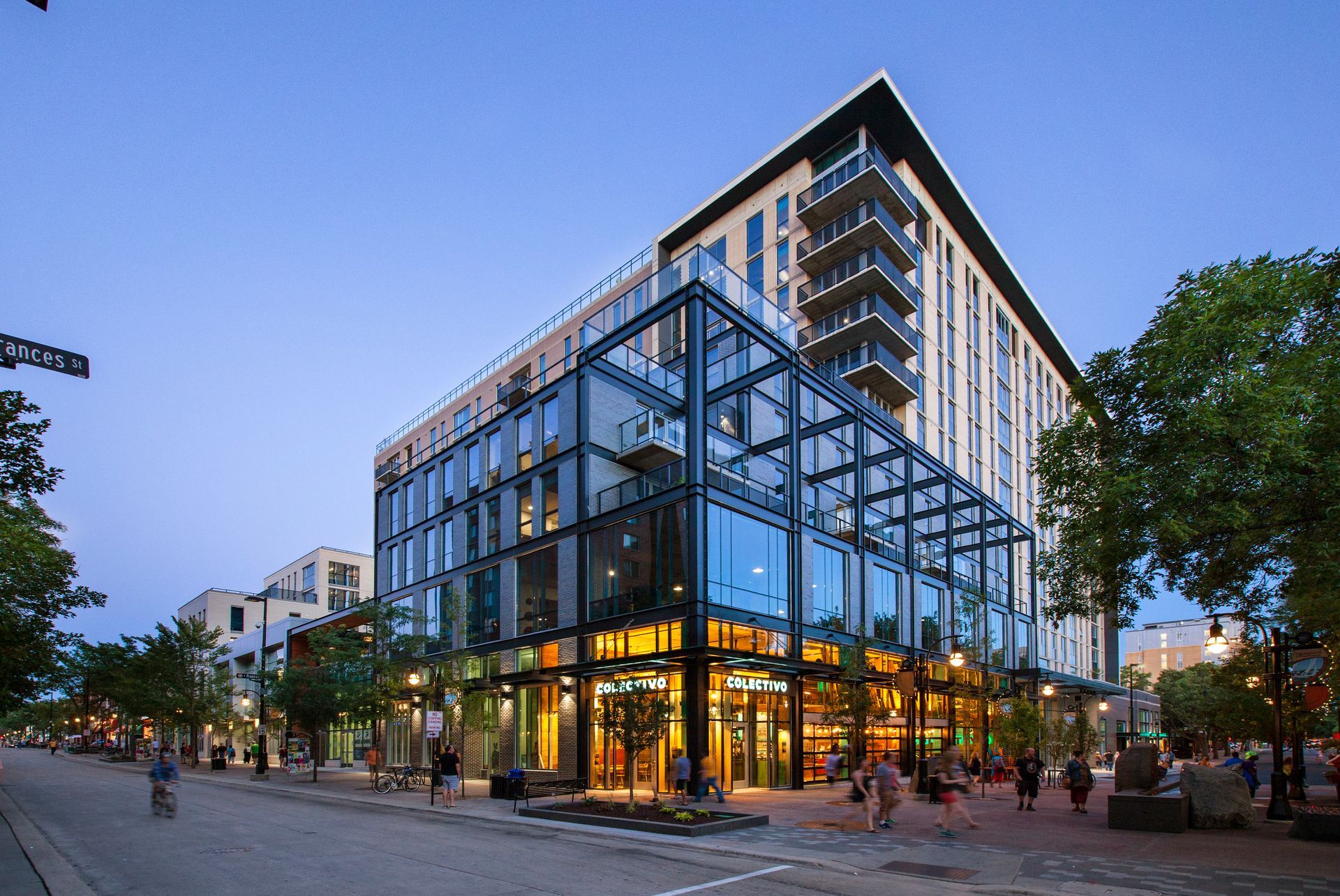 A large building with a lot of windows is sitting on the corner of a street.