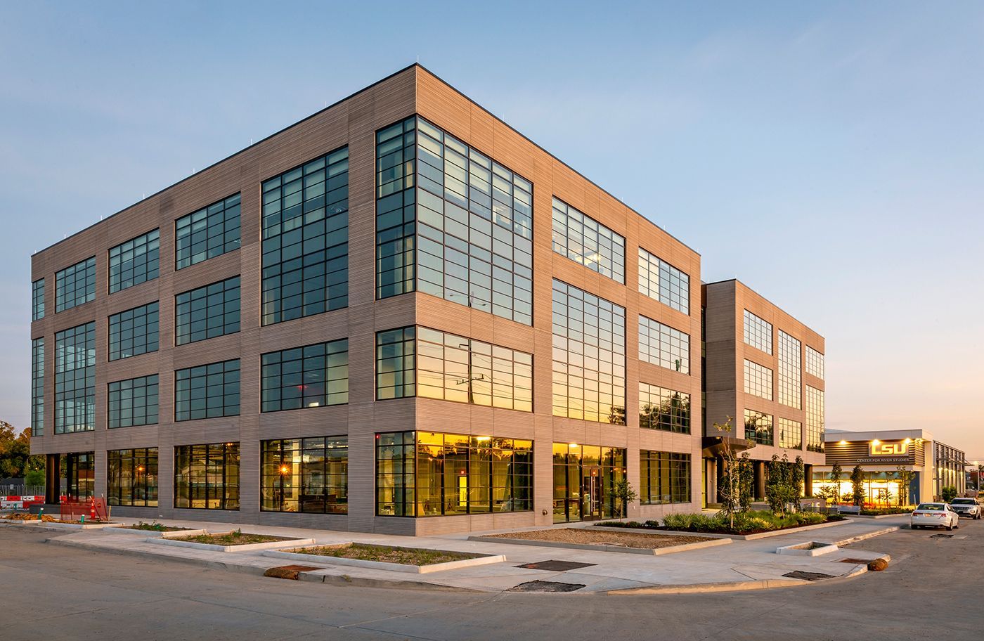 A large building with a lot of windows is sitting on the corner of a street.