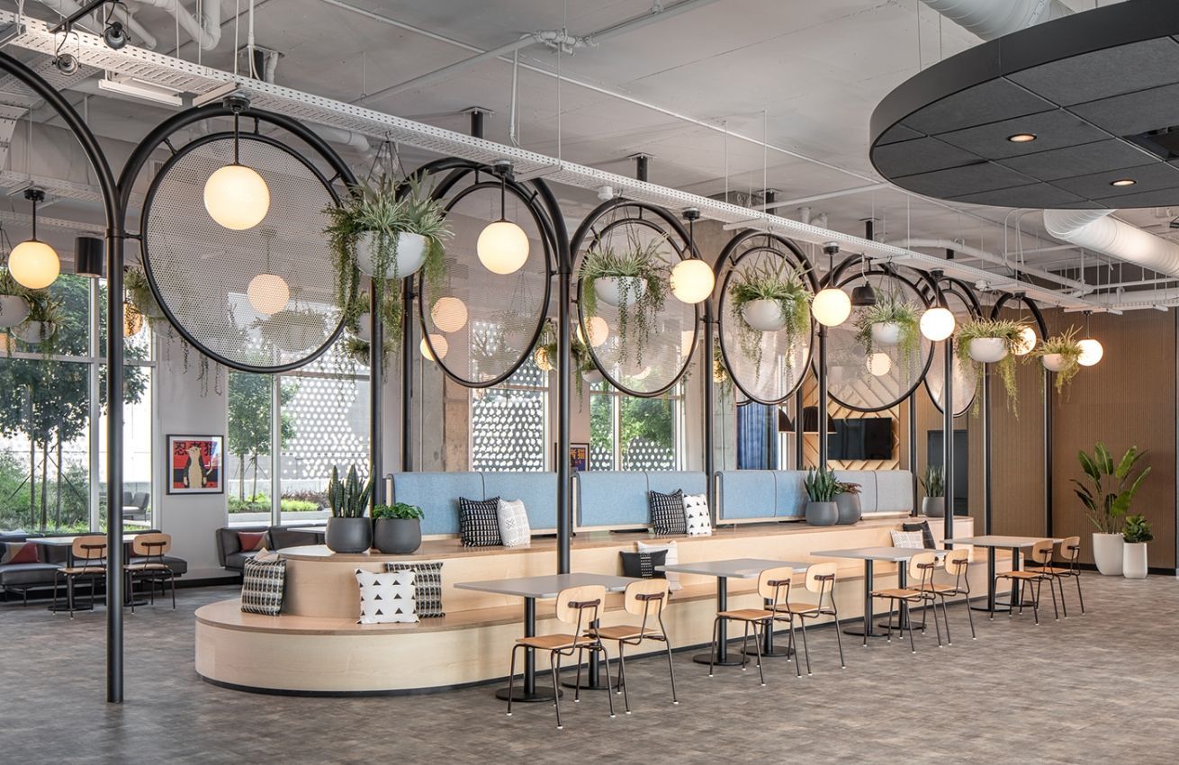 A large room with tables and chairs and plants hanging from the ceiling.