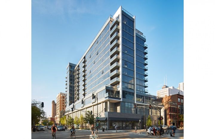 A large building with a lot of windows is sitting on the corner of a city street.