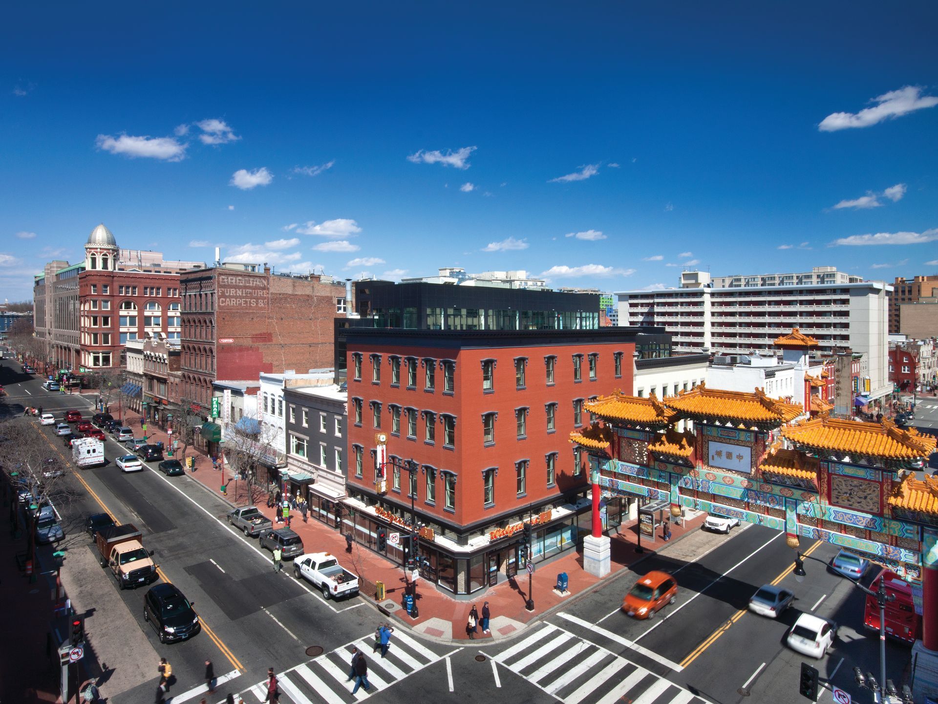 An aerial view of a city street with a red building in the middle