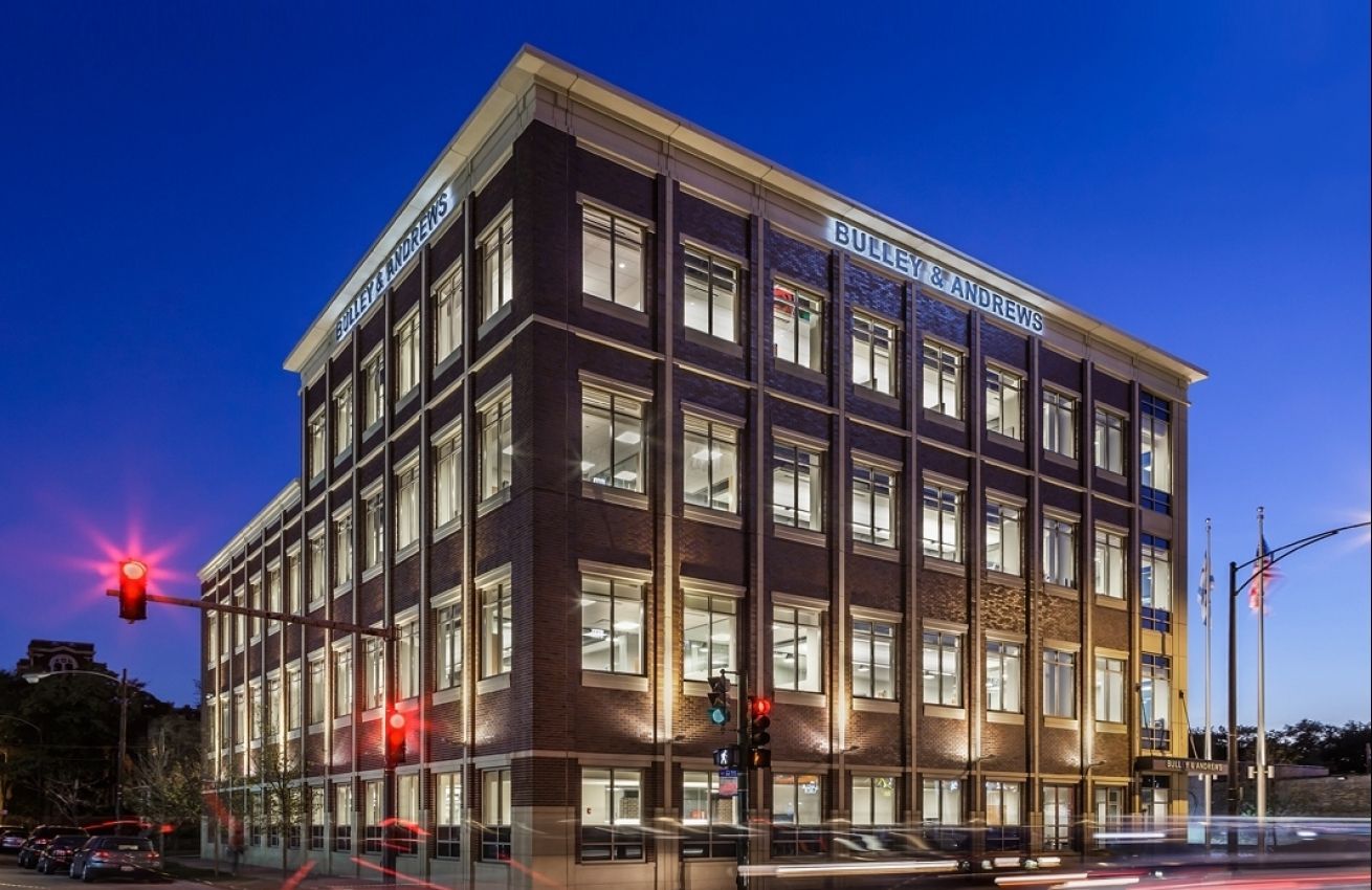 A large brick building with a lot of windows is lit up at night.