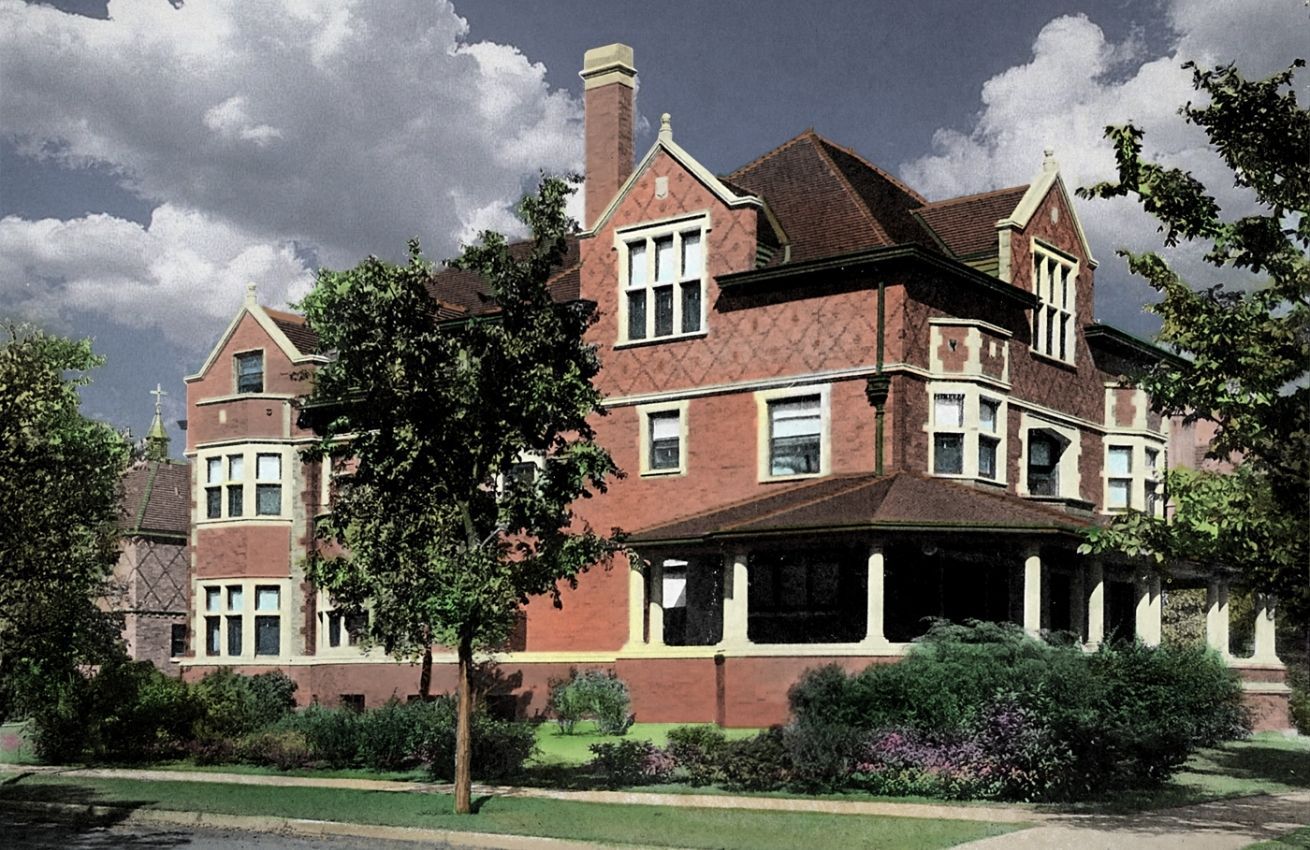 A large brick house with a porch and trees in front of it