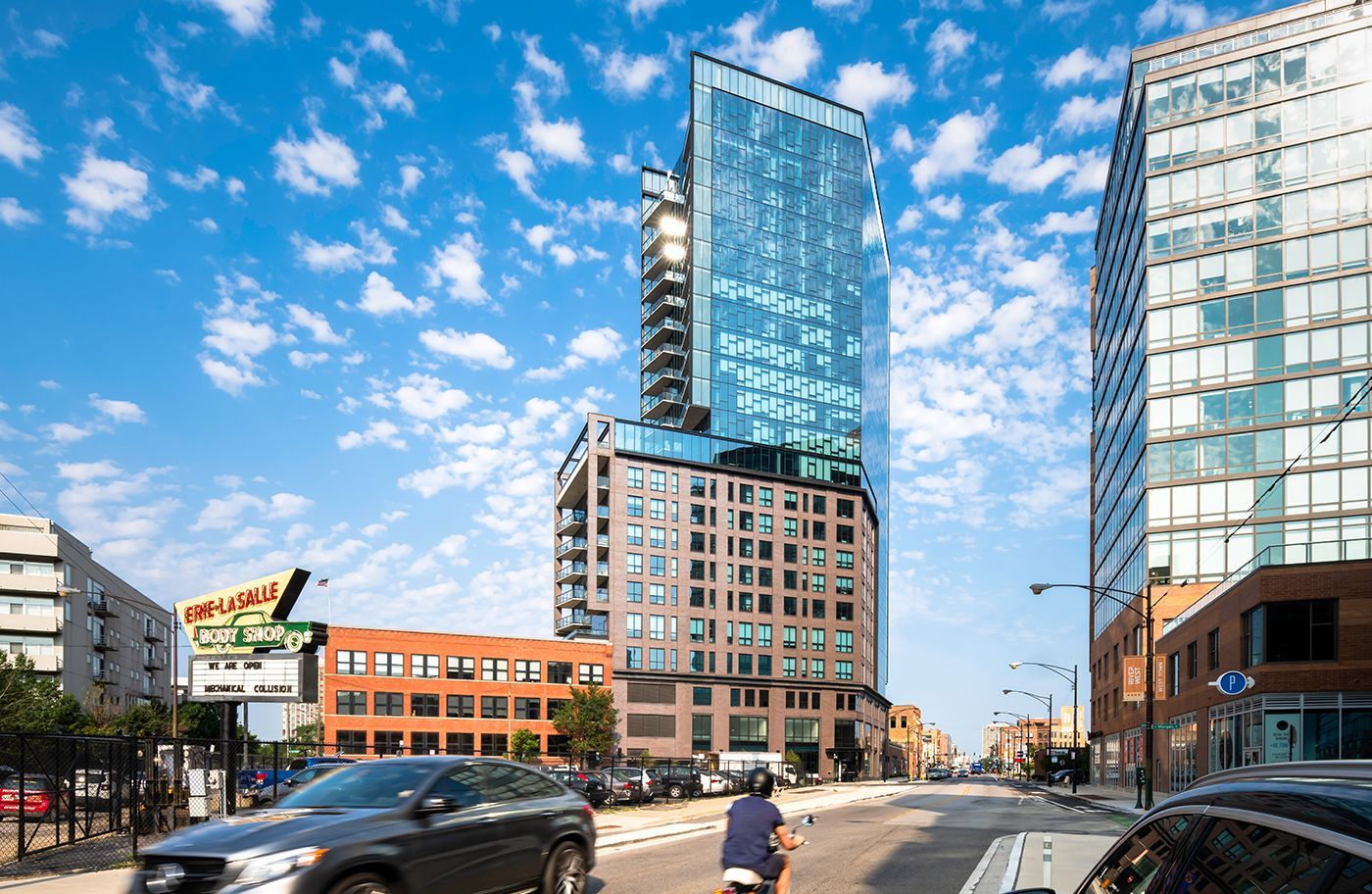 A man is riding a bike down a city street in front of a tall building.