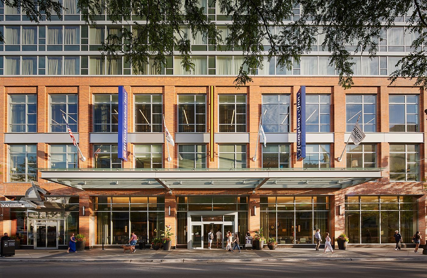 A large brick building with a lot of windows and people walking in front of it.