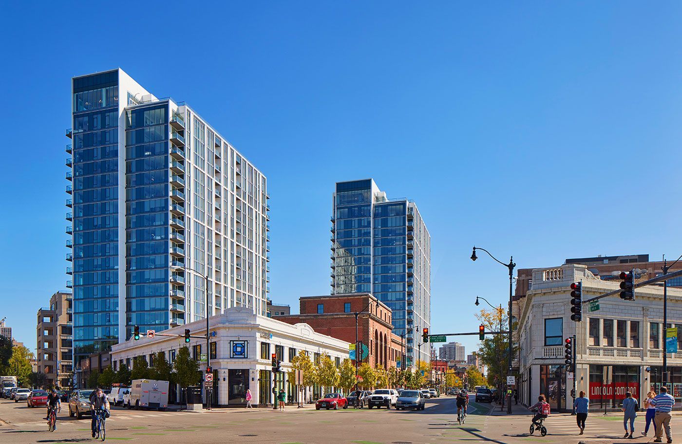A city street with a lot of tall buildings and people walking on the sidewalk.