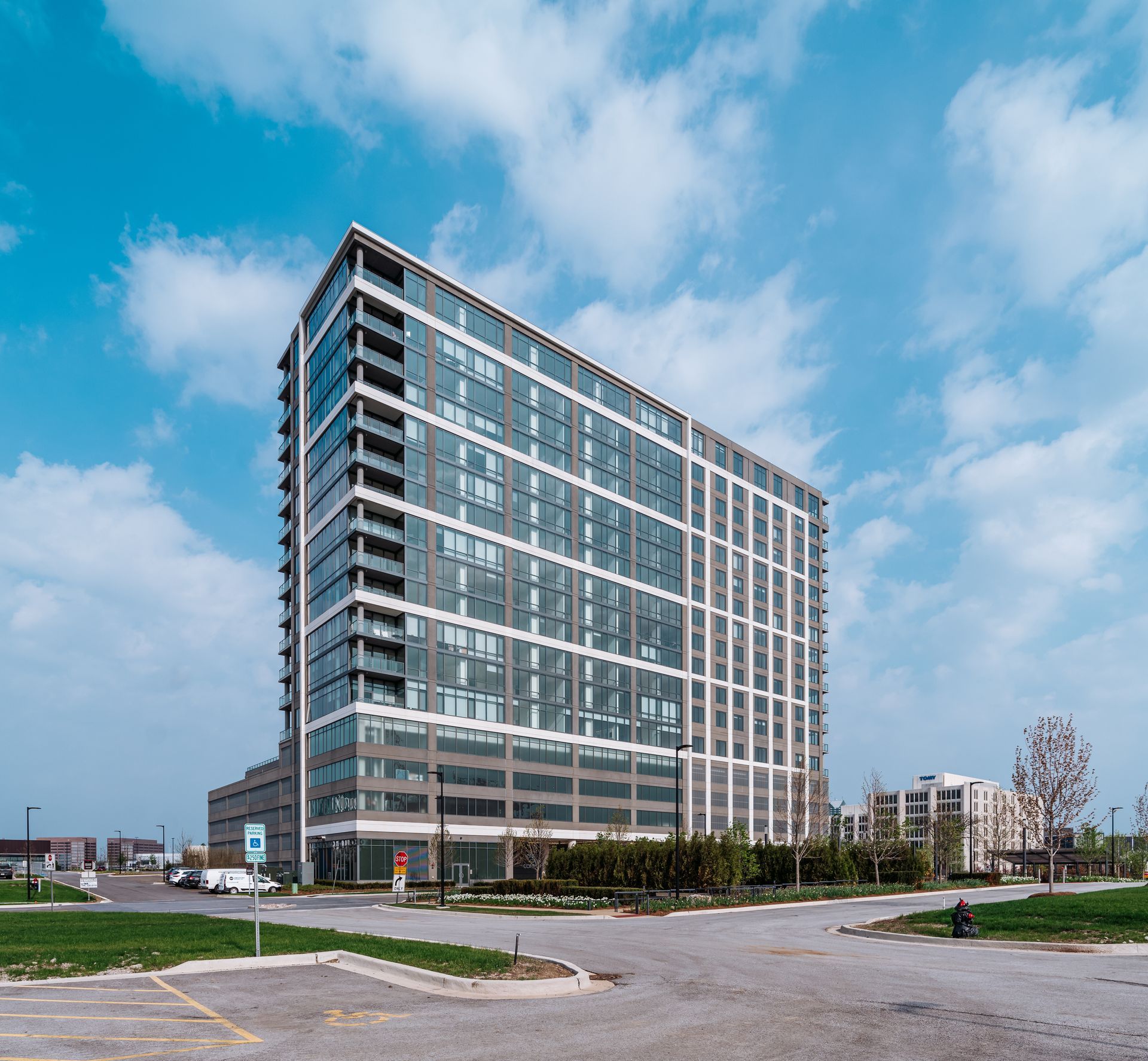 A large building with a lot of windows and a parking lot in front of it.