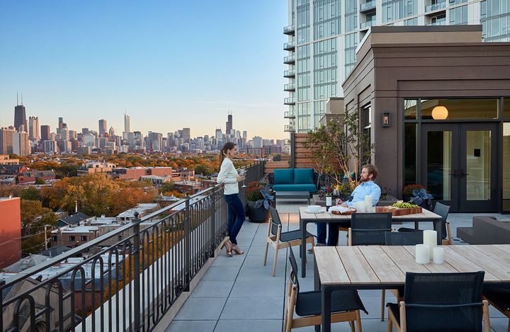 A man and a woman are sitting at a table on a balcony overlooking a city.