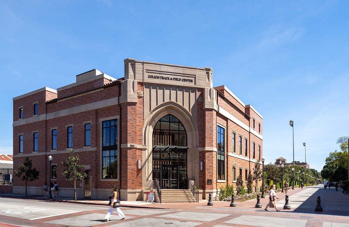 A large brick building with a lot of windows and people walking in front of it.