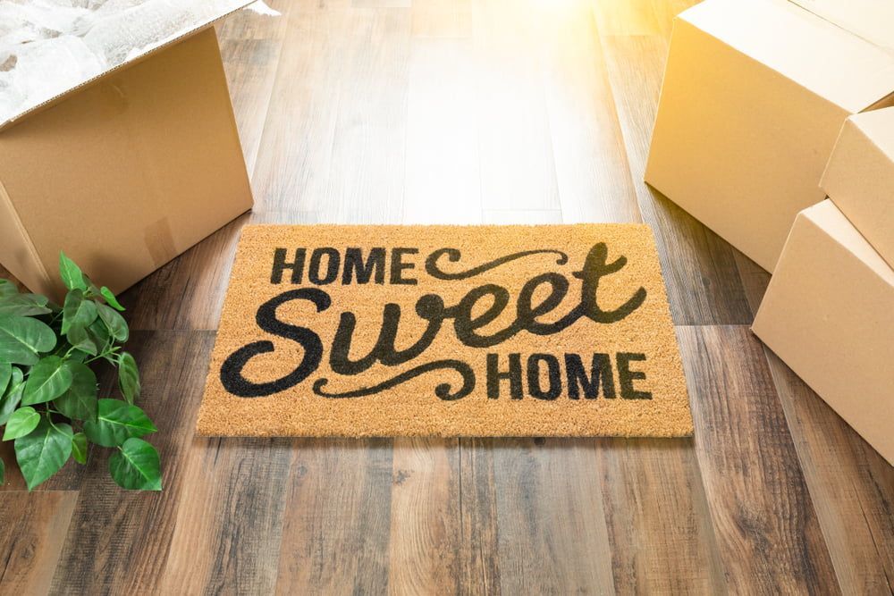 Door mat on wooden floor beside cardboard boxes - Alstonville Removalist