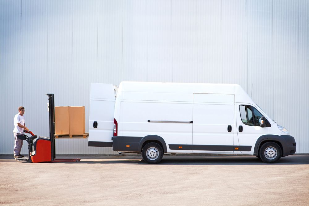 A Delivery Man Is Loading Boxes Into A White Van — Professional Removalists In Alstonville