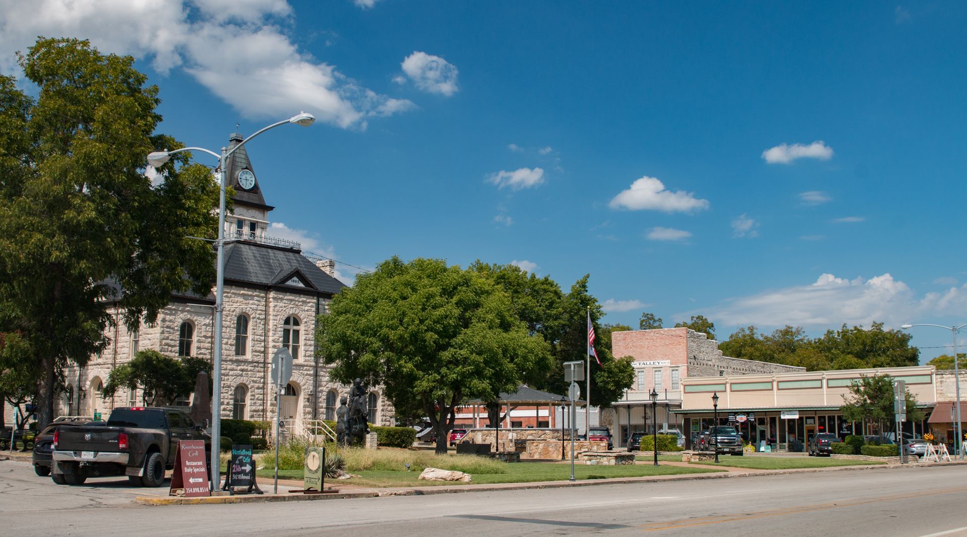 A large stone building with a clock tower is in the middle of a small town.