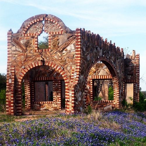 A brick building is surrounded by purple flowers