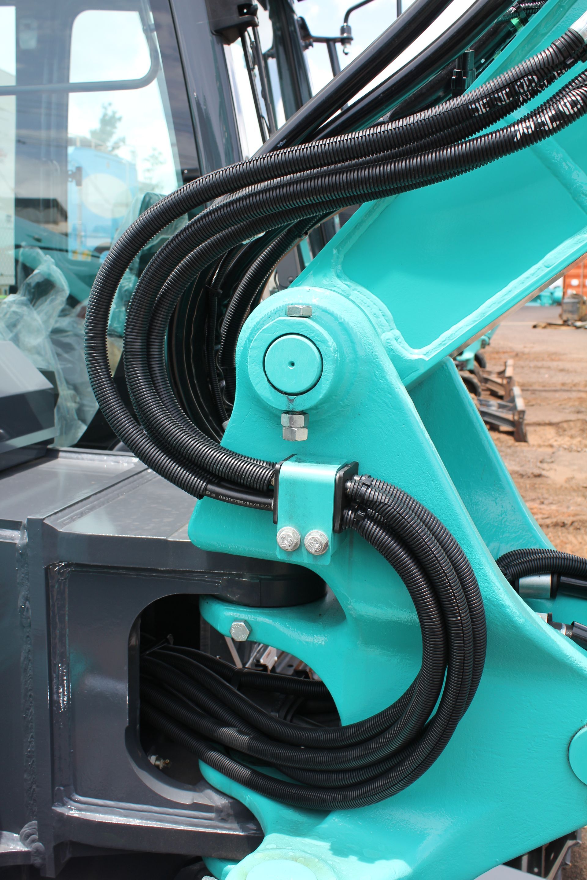 Aqua-colored excavator arm with black hoses attached. Steel bracket with bolts is visible — Forecast Machinery in Yarrawonga, NT