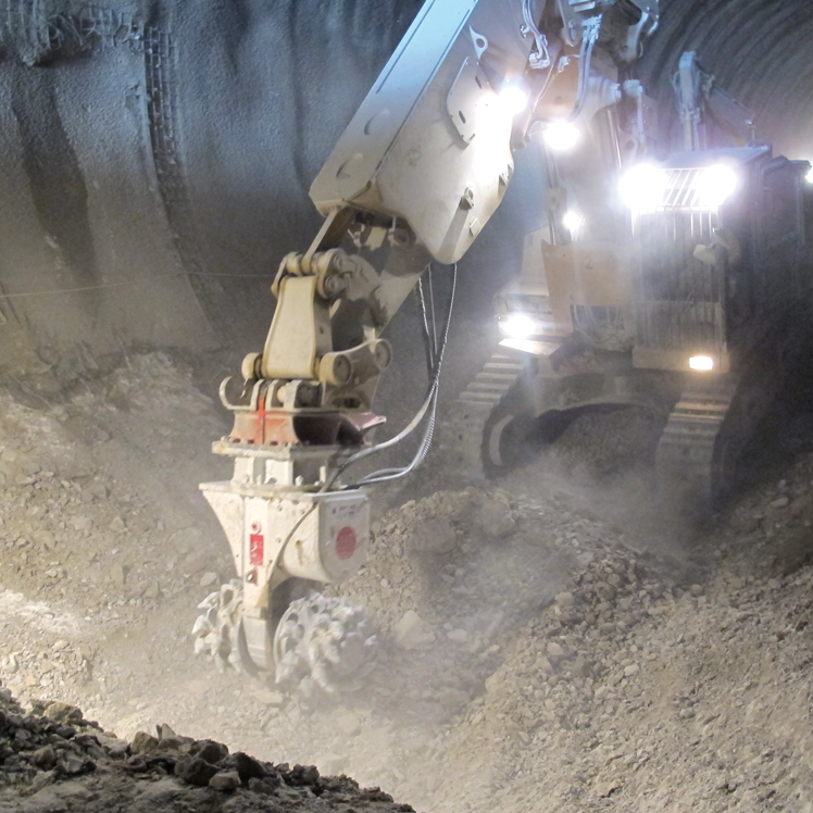 A roadheader machine excavating a rock tunnel, using its rotating cutter head to break ground under bright lights — Forecast Machinery in Yarrawonga, NT