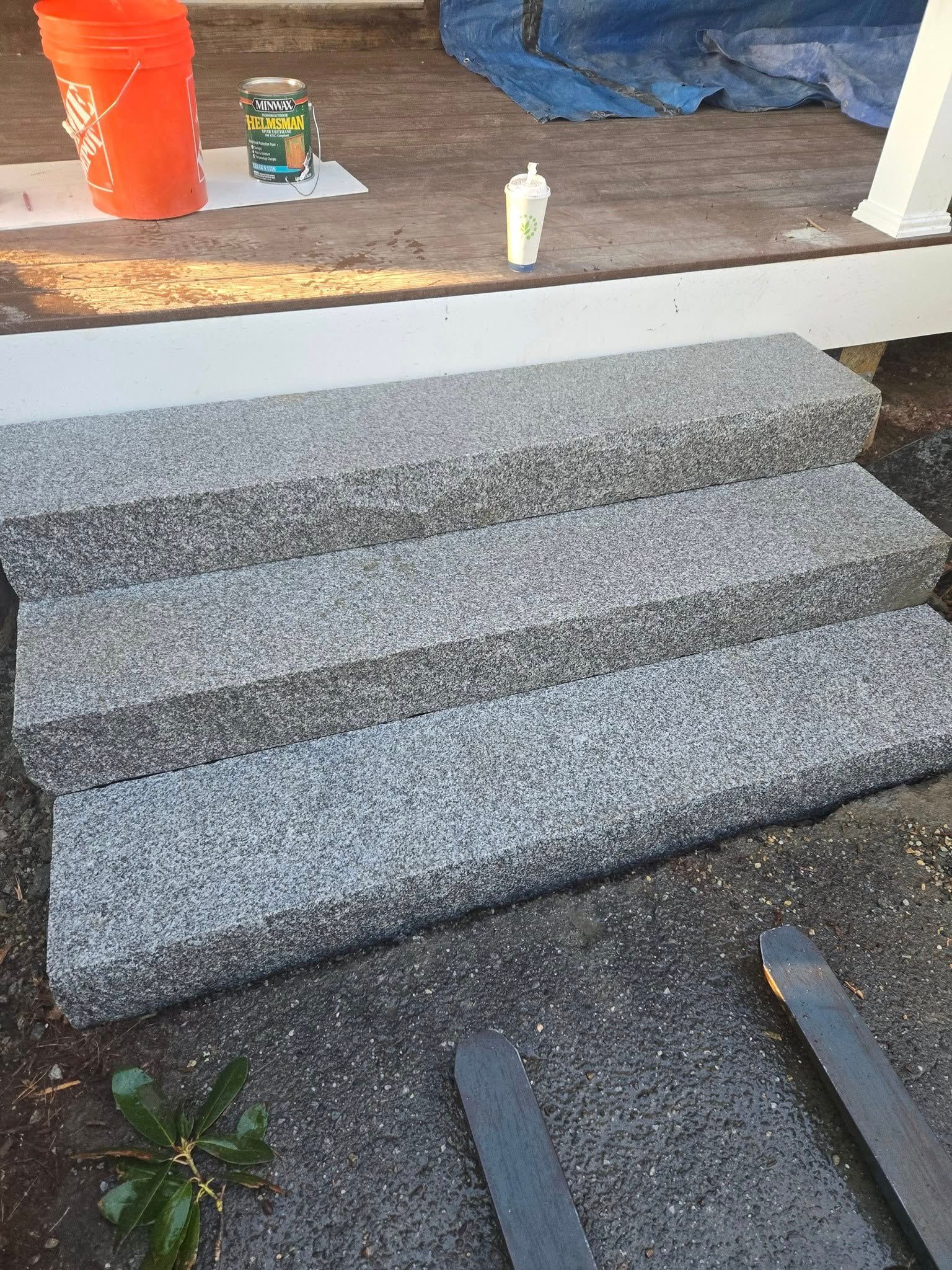 Three gray granite steps leading to a white porch. Orange bucket and glue bottle visible.