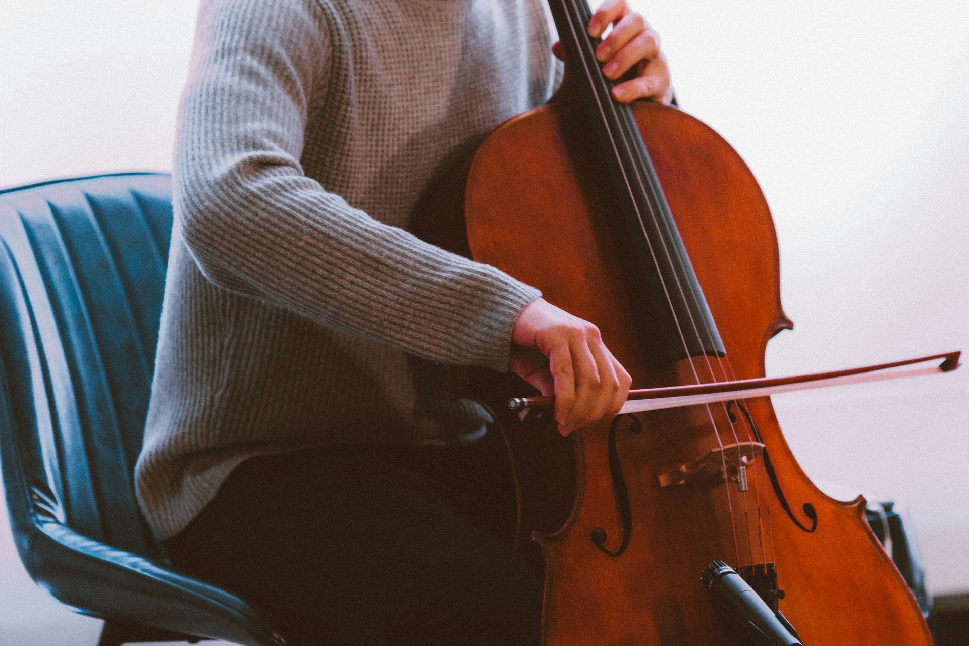 Imagem em close-up de um violino sendo tocado, com dedos pressionando as cordas de um instrumento de madeira aquecido.
