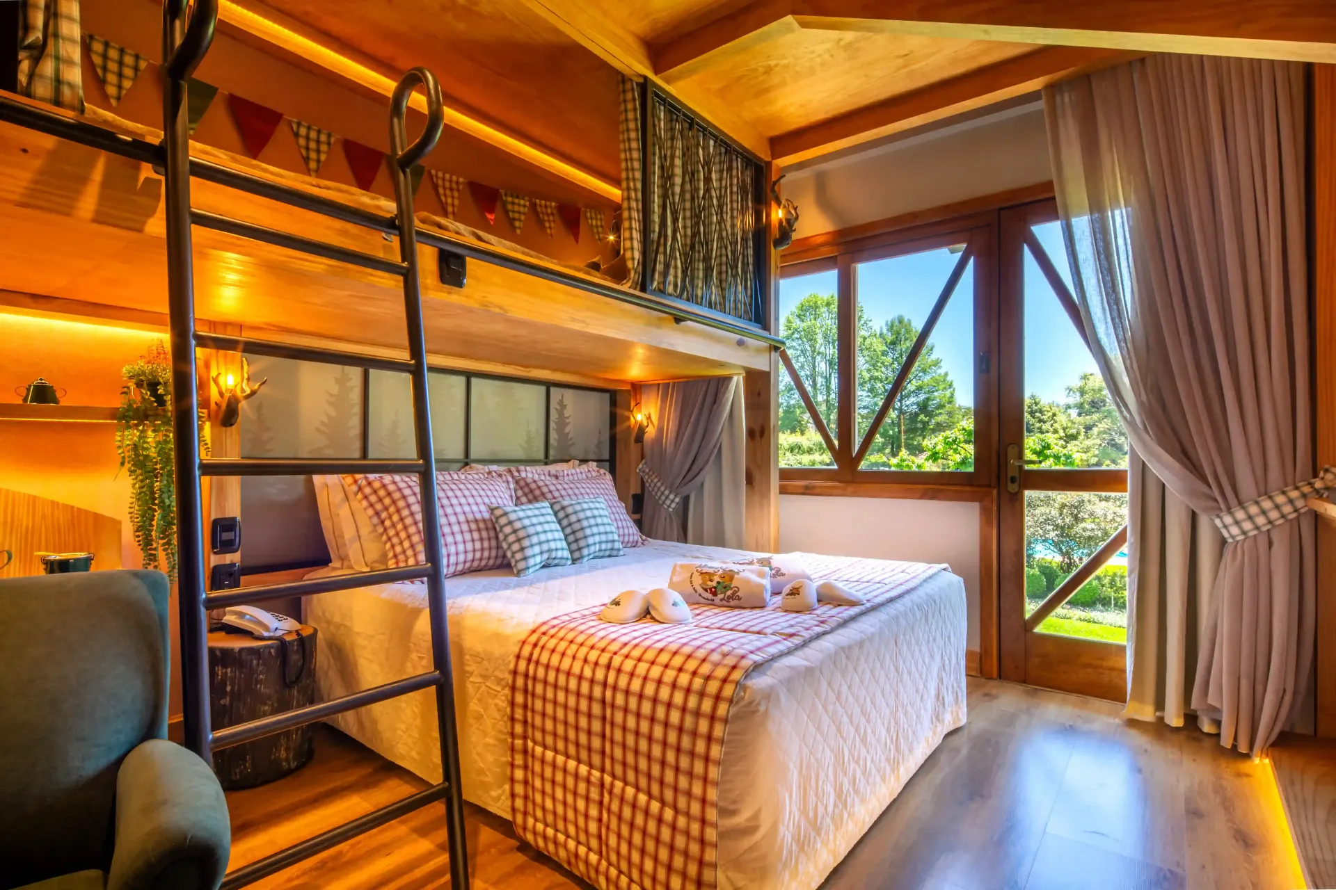 Quarto aconchegante com beliche de madeira, iluminação quente e grandes janelas com vista para a vegetação.