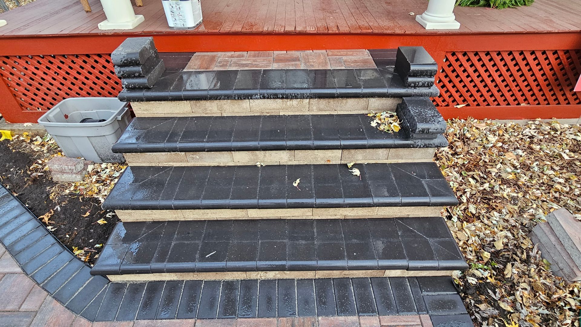 Black construction staircase with leaves, beside an orange barrier and building wall