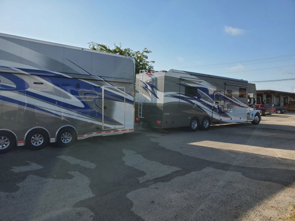 Two large trailers parked outdoors; one is silver/blue, the other gray/silver.