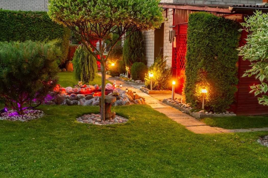 A lush green lawn with a path leading to a house at night.