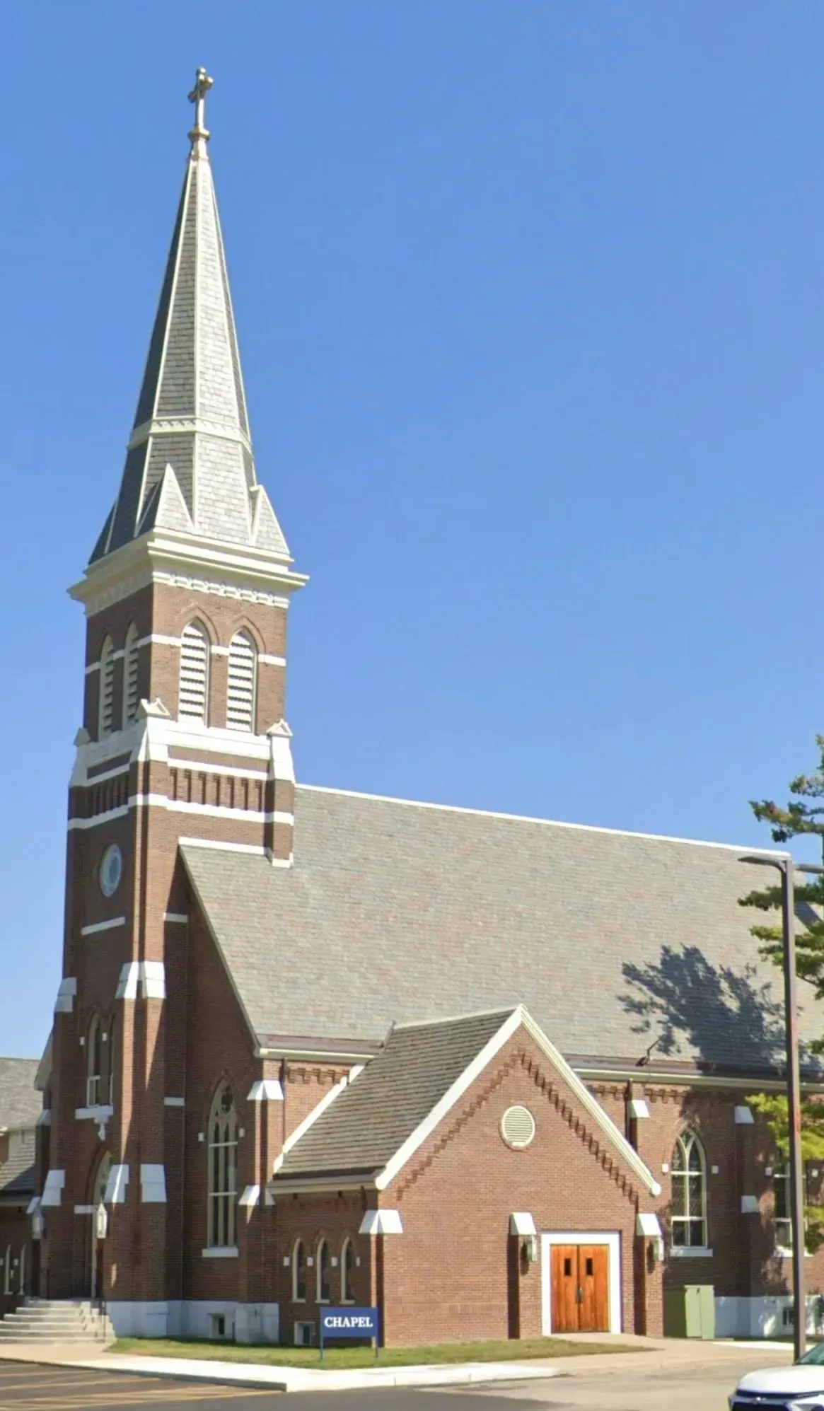 Brick church with tall green steeple against a blue sky