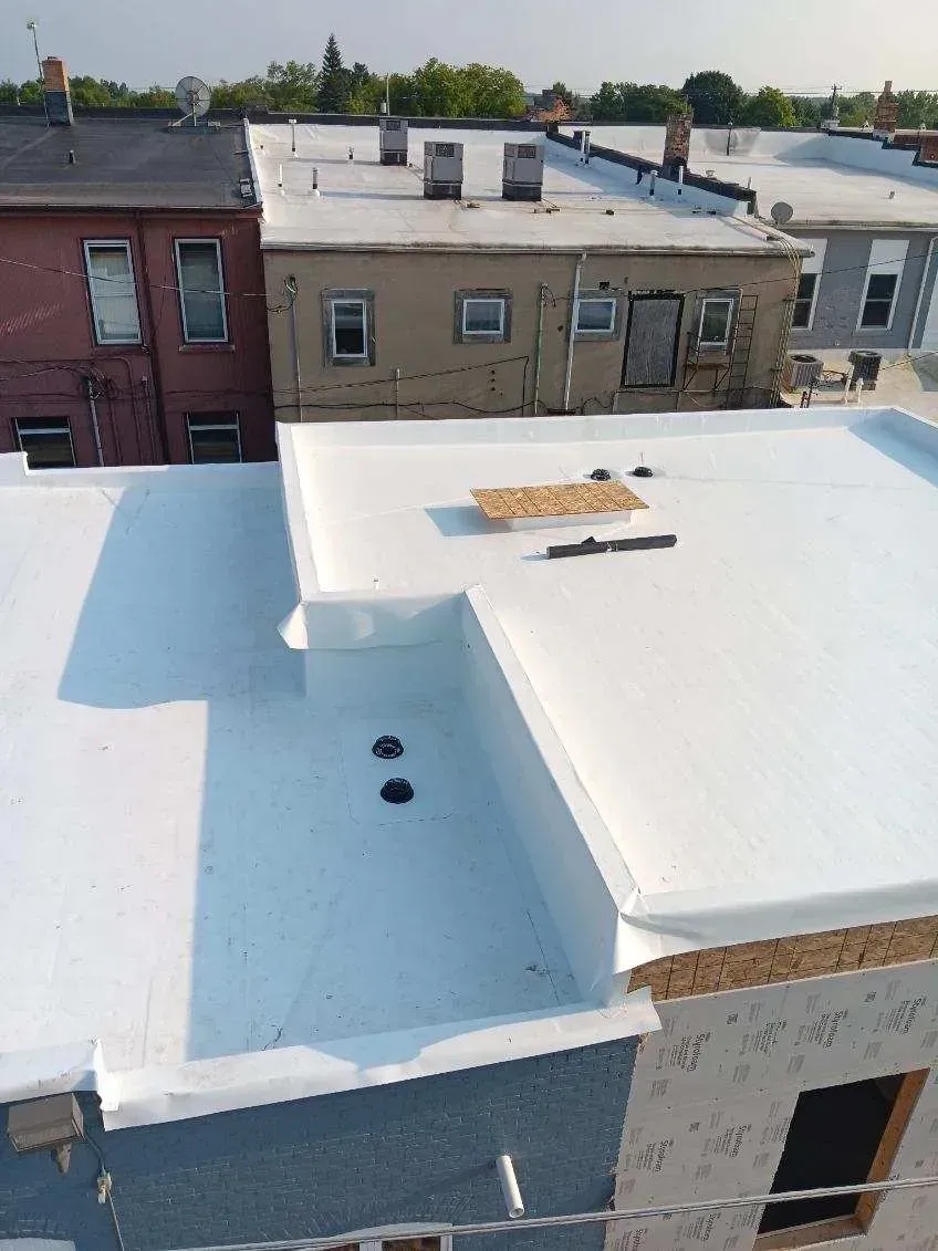 White flat rooftops of row houses with vents and a hole in the roof under a clear sky
