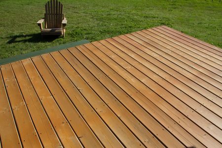 Wooden deck extending into a grassy yard with an Adirondack chair in the background