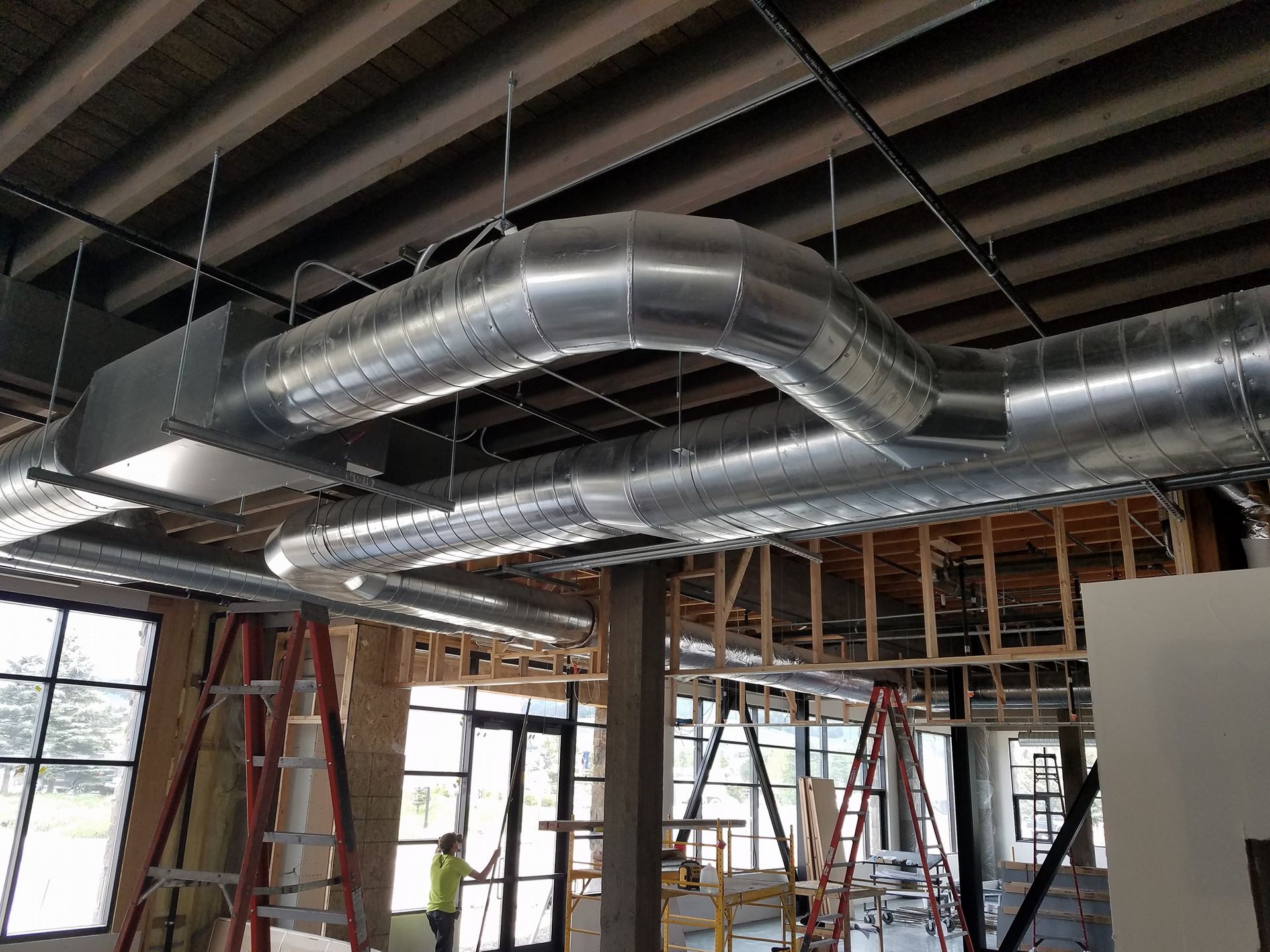 A building under construction with a lot of pipes hanging from the ceiling