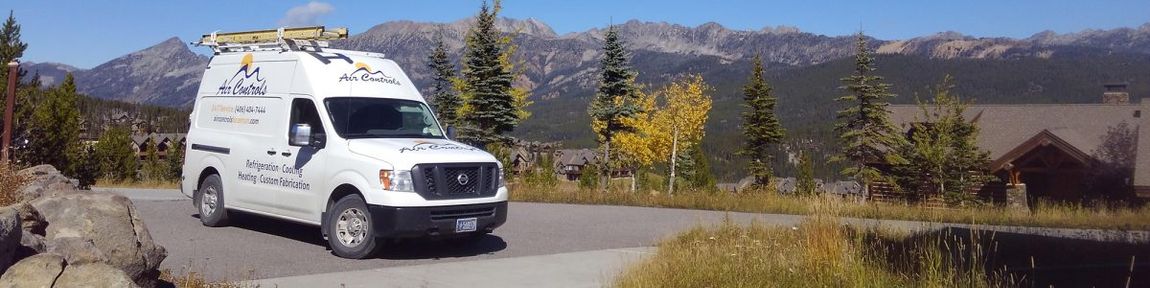 A white van is driving down a road with mountains in the background