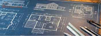 A professional architectural blueprint of a custom home lying on a wooden table with drafting tools.