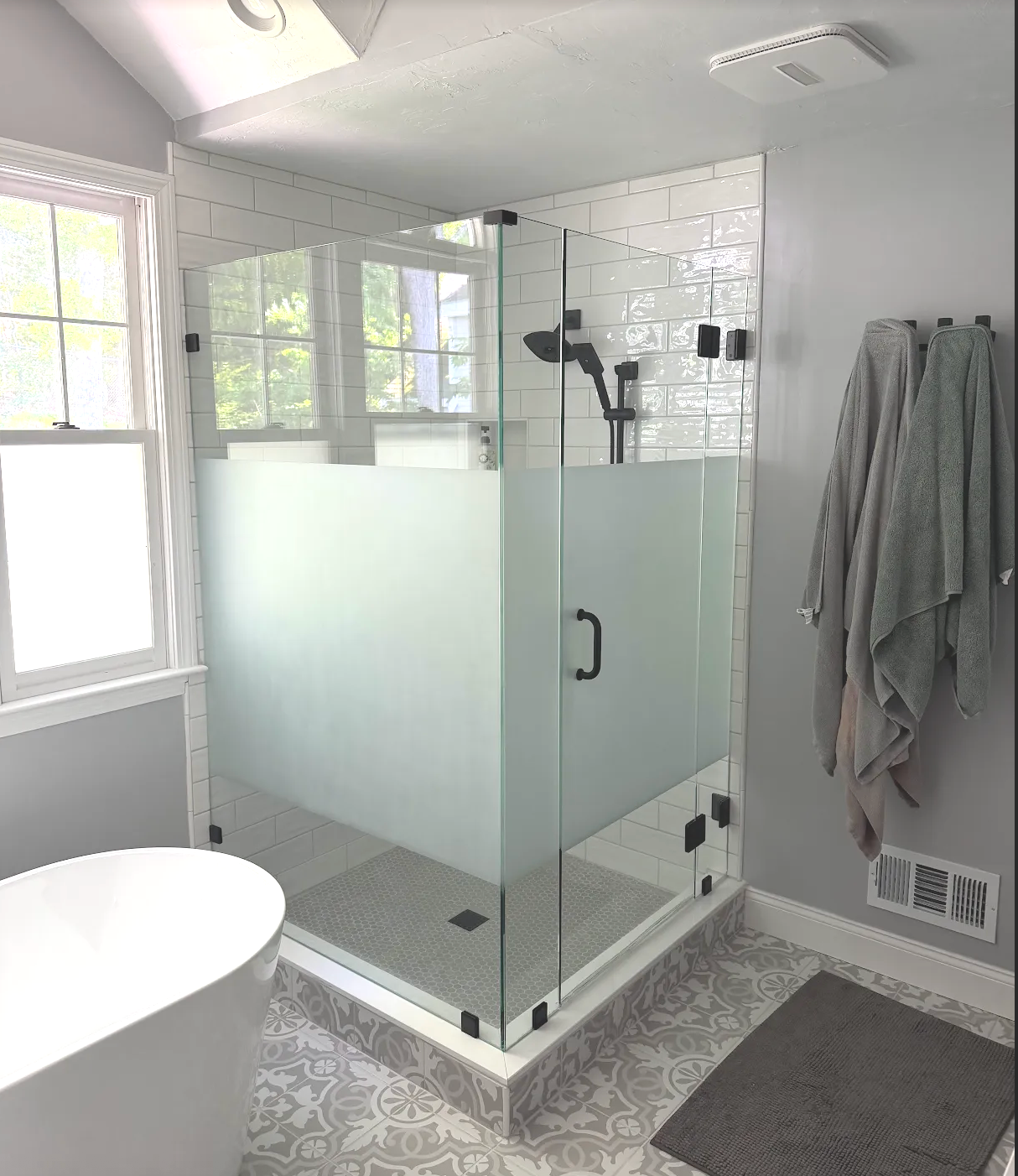 Frosted privacy glass shower enclosure next to a freestanding tub
