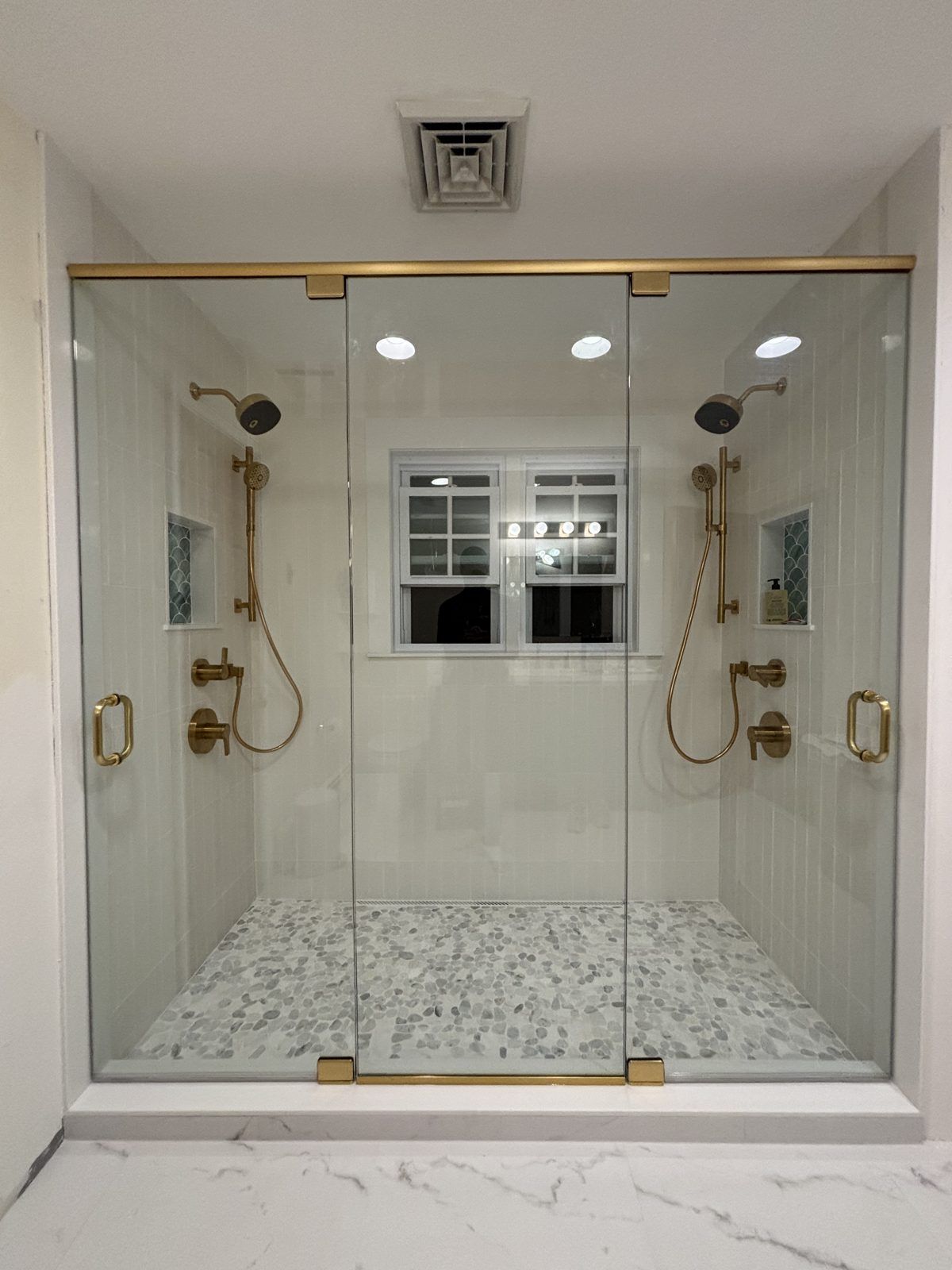 Frameless double hinged shower doors with brushed gold hardware, Wellesley, MA