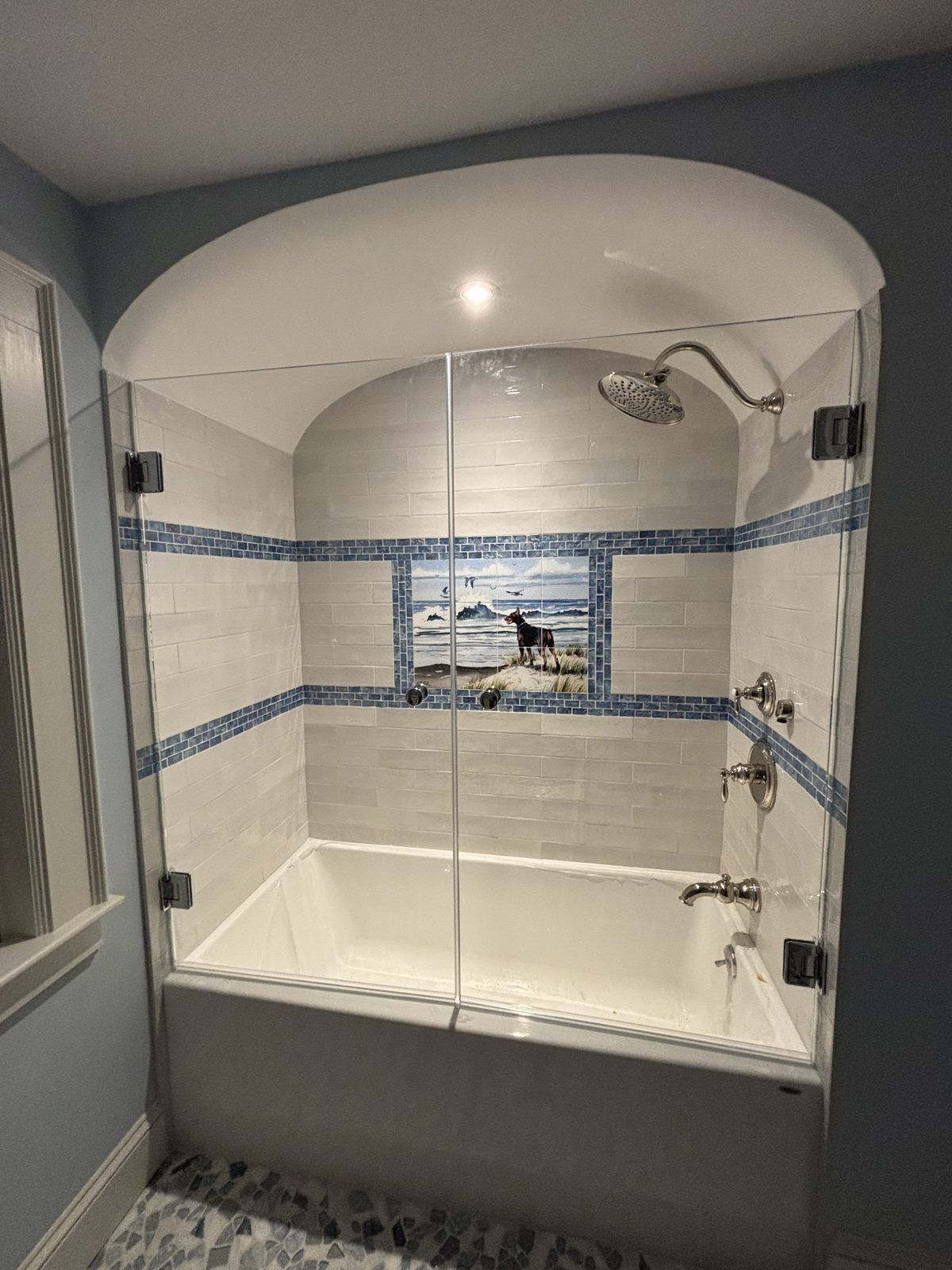 Frameless glass bathtub enclosure with hinged door in an arched alcove, Sandwich, MA