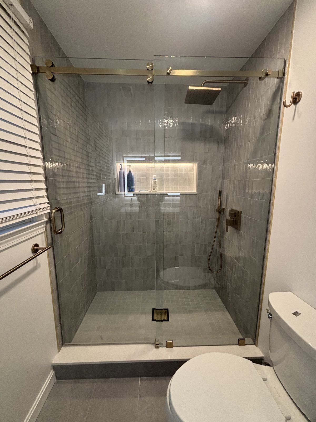Frameless sliding shower door with brushed gold hardware, Milton, MA
