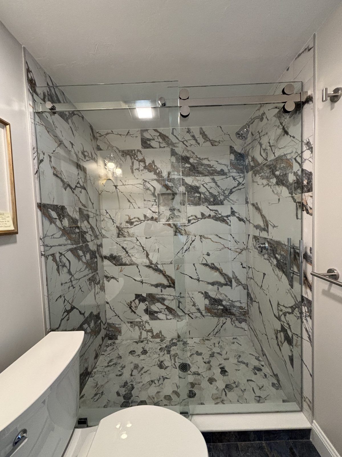 Frameless sliding shower door with marble tile walls, Quincy, MA