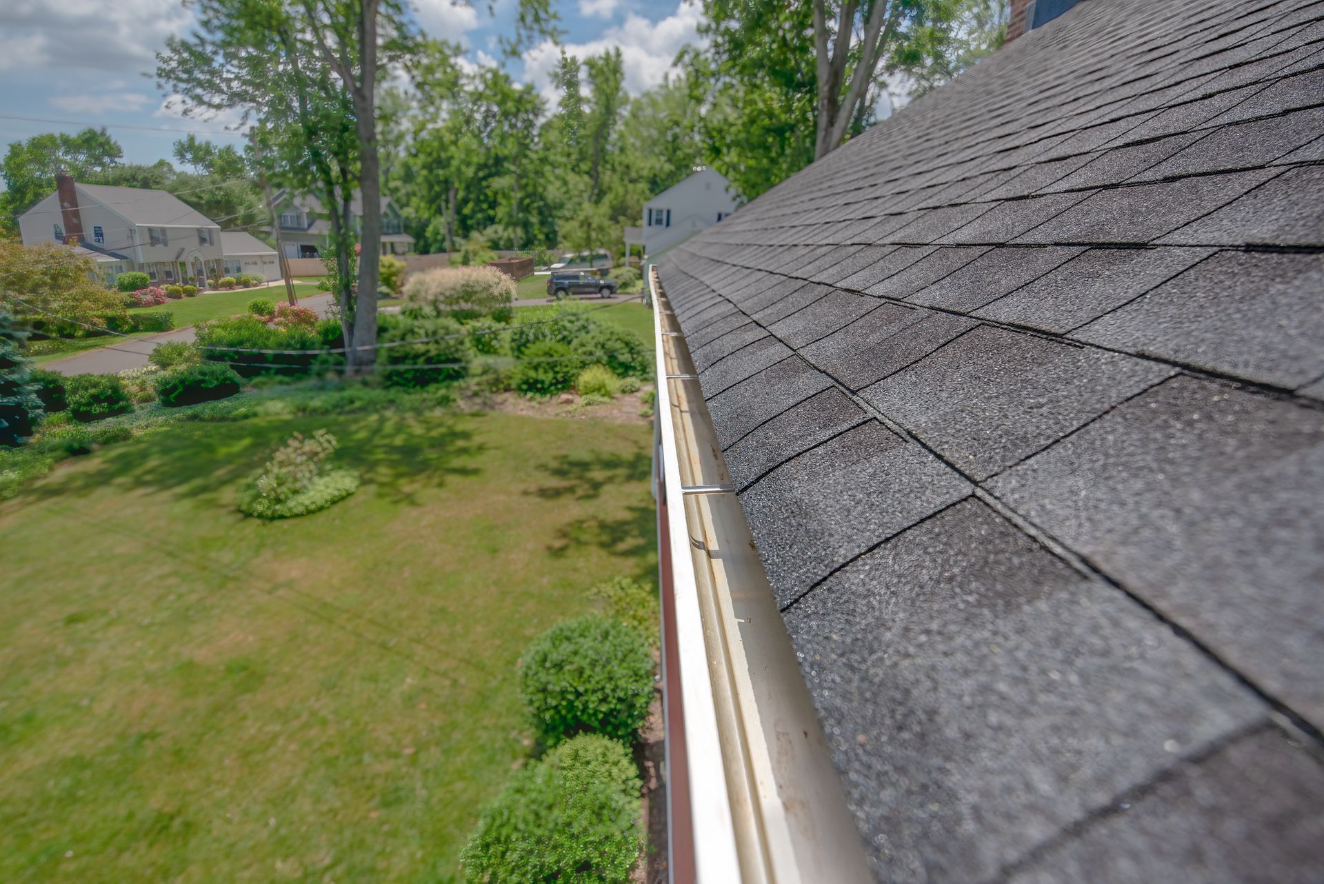 Leaf gutter guard under a shingled roof edge with mounting clips