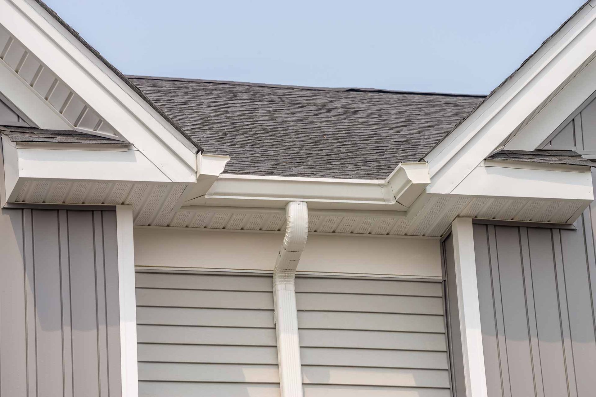 House roof with visible gutter damage and a hanging downspout between two gables
