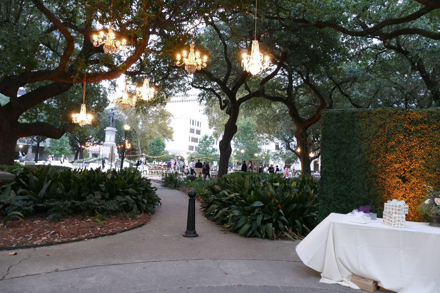 A table in a park with trees and chandeliers hanging from them