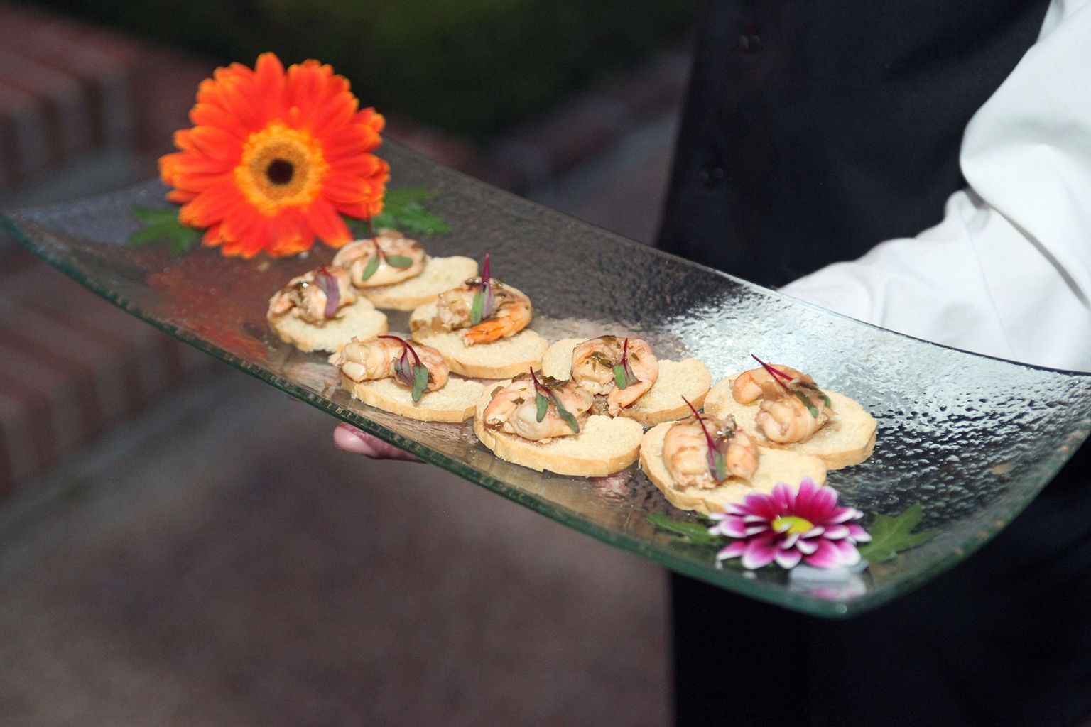 A person is holding a plate of food with flowers on it.